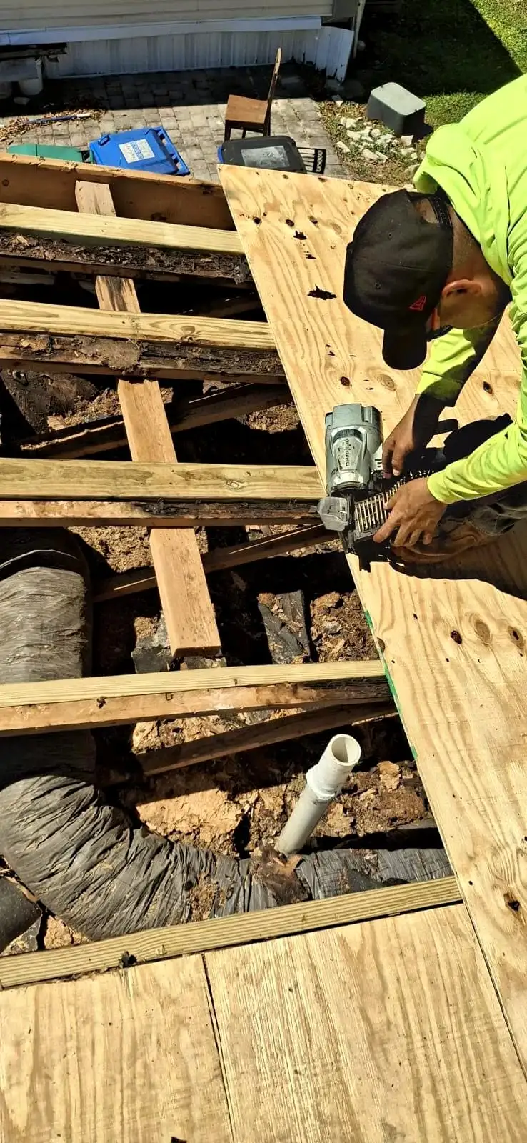 A roofer fastening new plywood over the rafters where the old decking came off